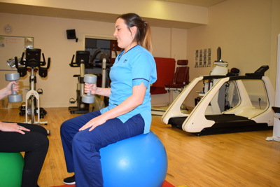 nurse sitting on exercise ball with weight in her hand