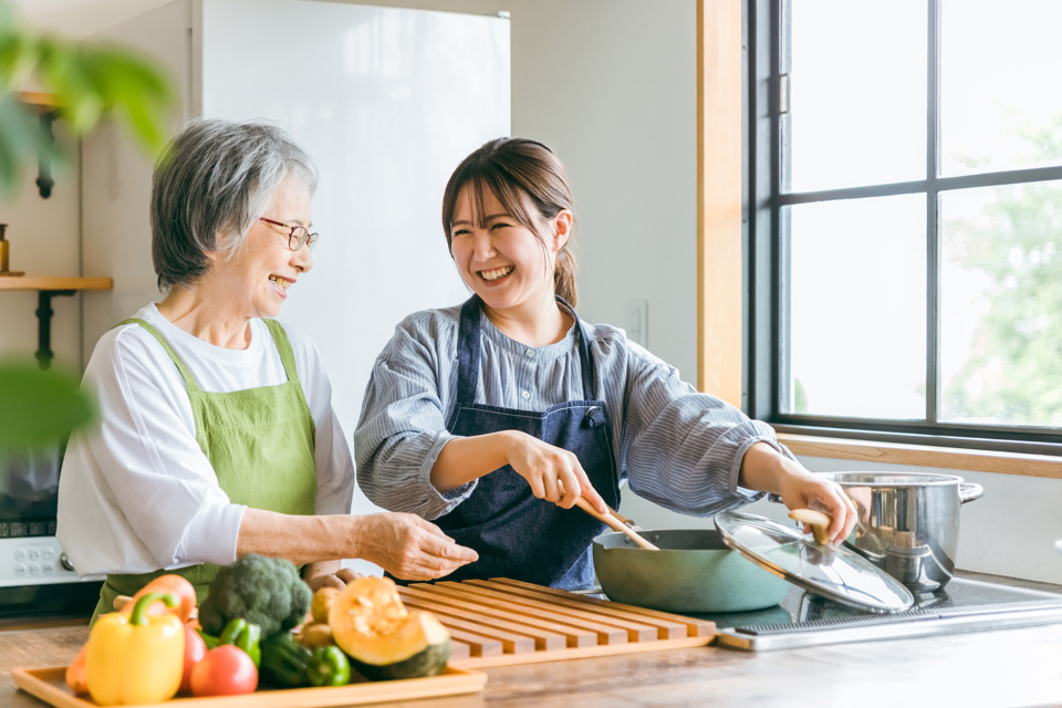 Woman cooking vegetables with younger woman