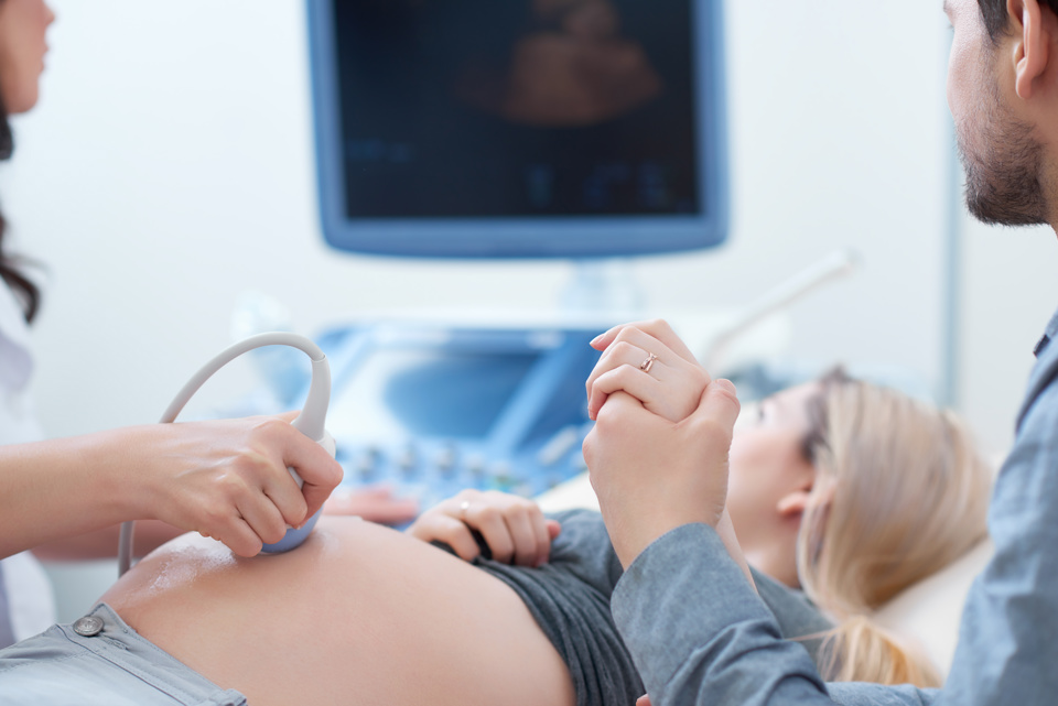 Woman getting baby scan holding partners hand