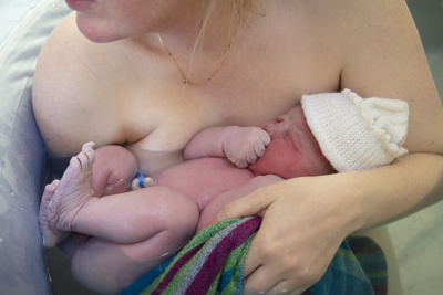newborn baby against mother in birthing pool