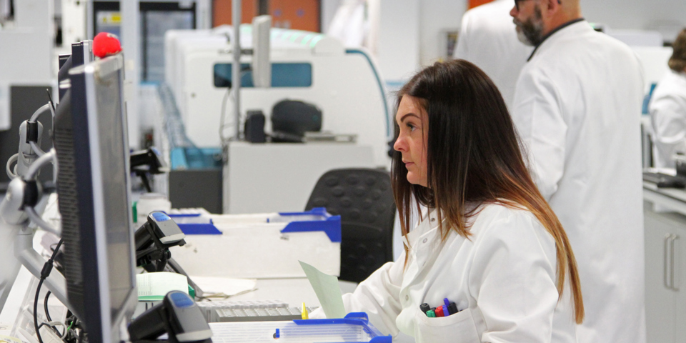 Woman dressed in labcoat looking at computer