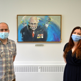 Man and woman beside portrait of captain Tom