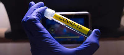 Gloved hand holding a test tube of covid-19
