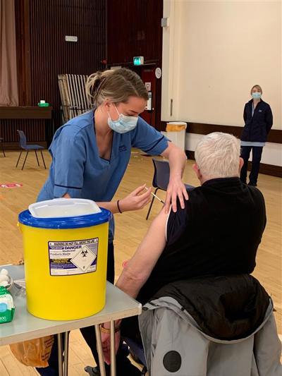 Nurse giving vaccine to older patient