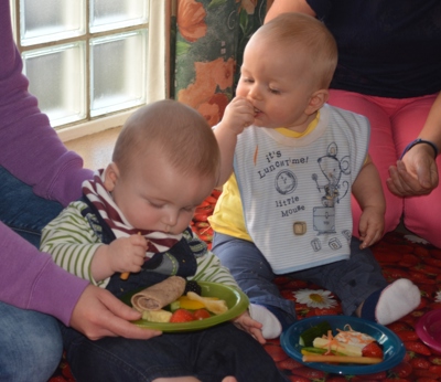 Two babies eating finger foods