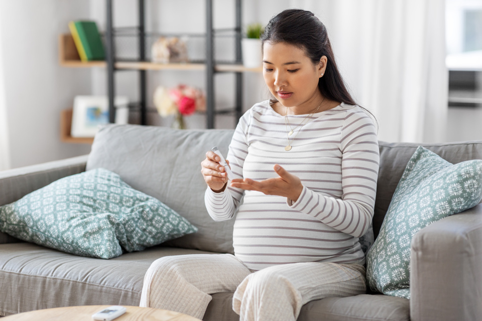 Pregnant lady testing blood sugar Adobestock 439810309