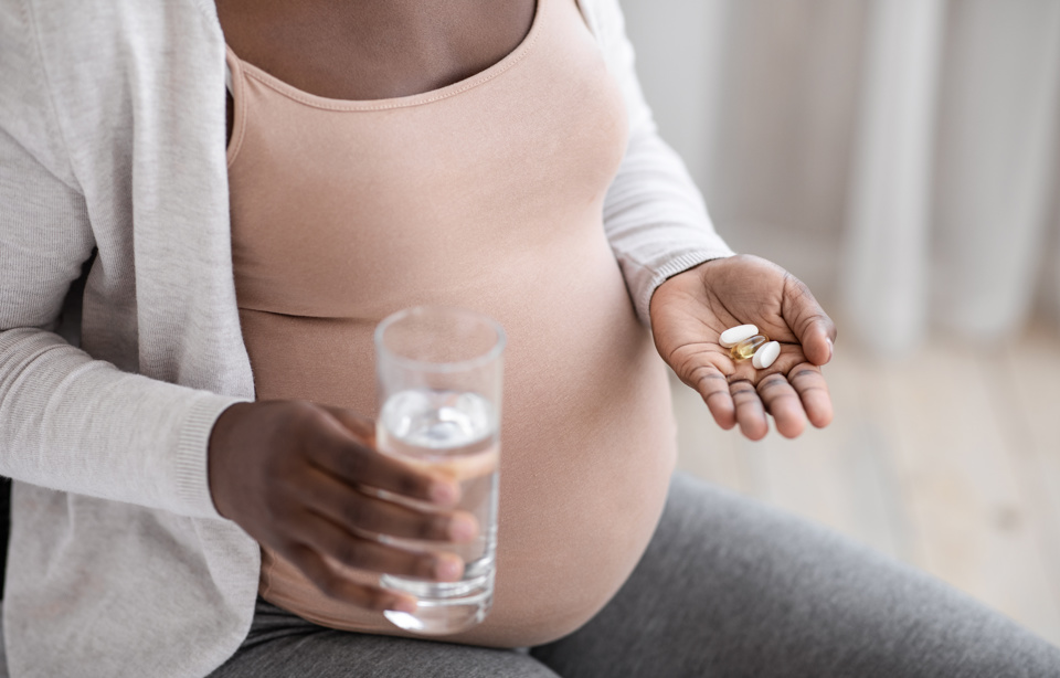 Pregnant woman talking pills Adobestock 385089284