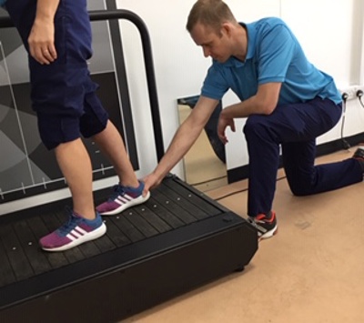 patient walking on treadmill with physio assistance