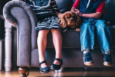 kids legs sitting on couch with dog sad