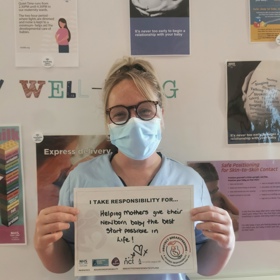 Nurse wearing mask holding sign about babies