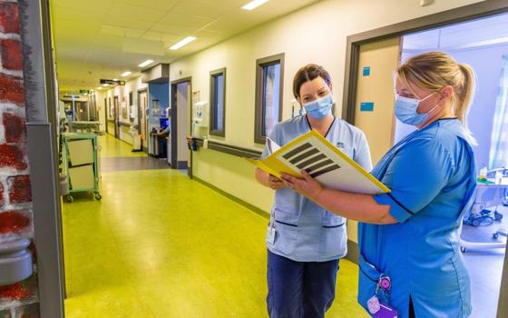 Nurses reading case notes in corridor