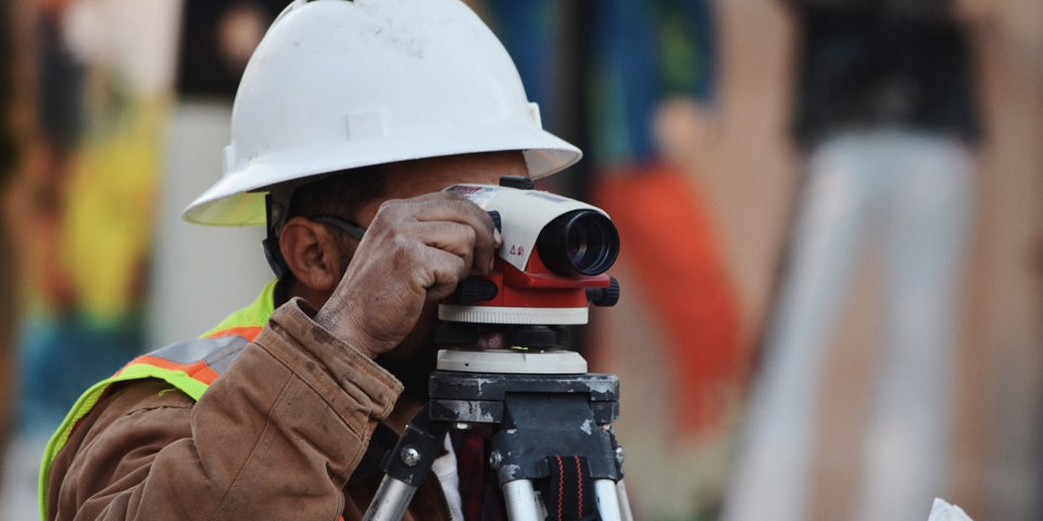 construction worker looking through surveying camera