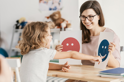 teacher with child pointing at smiley faces on paper