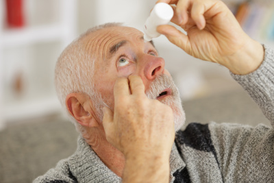 man giving himself eye drops