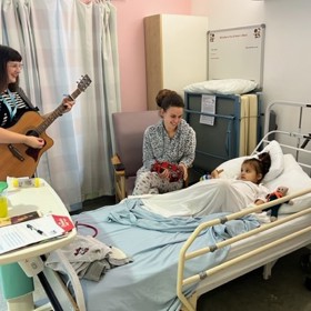 Playing guitar by bed of child