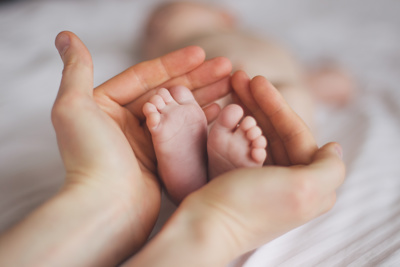 Hands cupping new-born babies feet