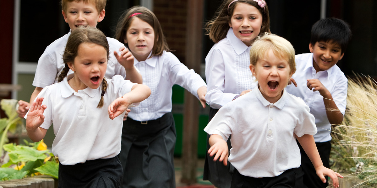 A group of school children run towards the camera.