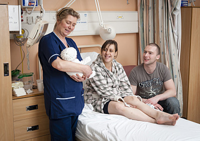 Healthcare  holds baby beside parents